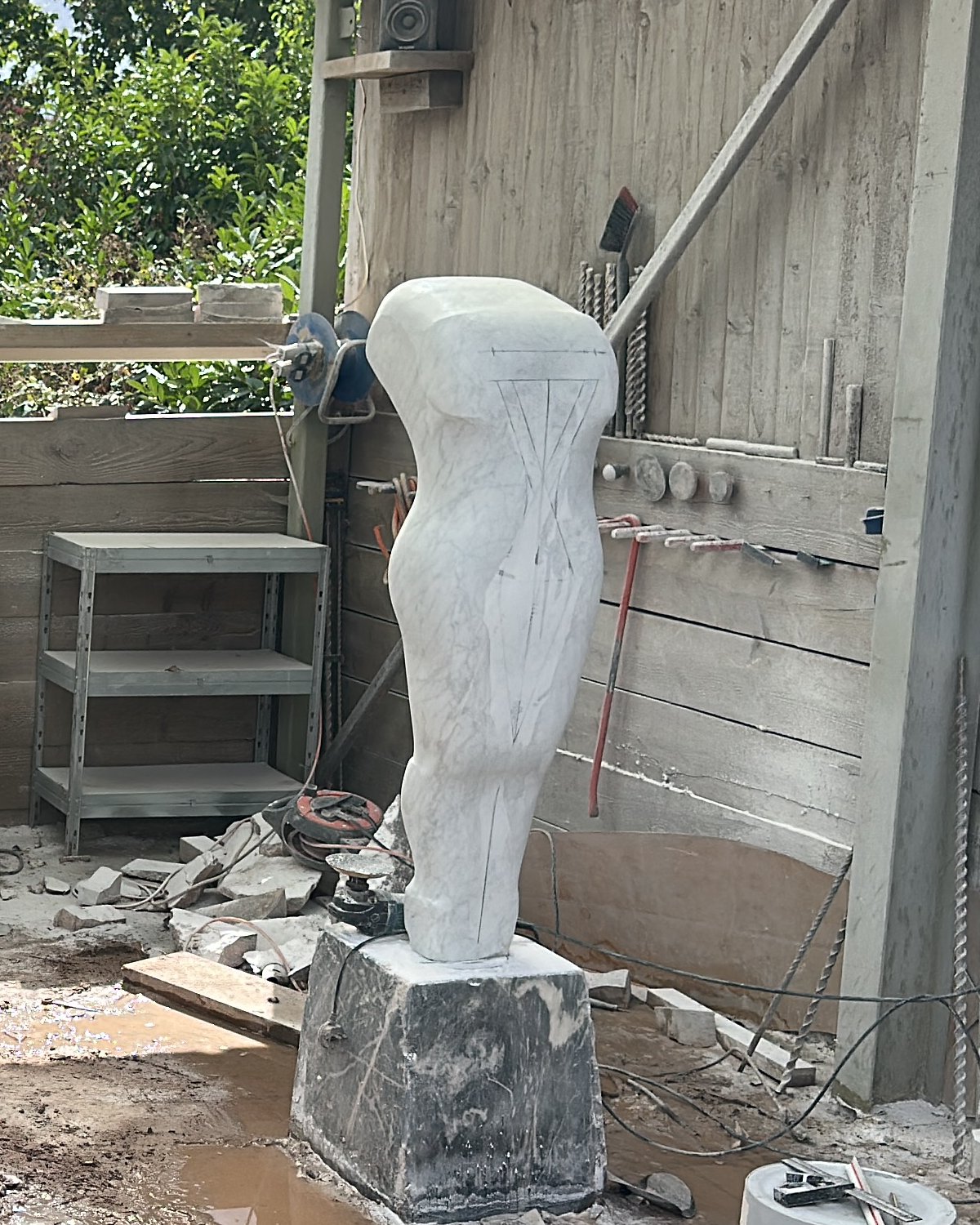 The rough white figure on its block in the workshop, marked with pencil lines