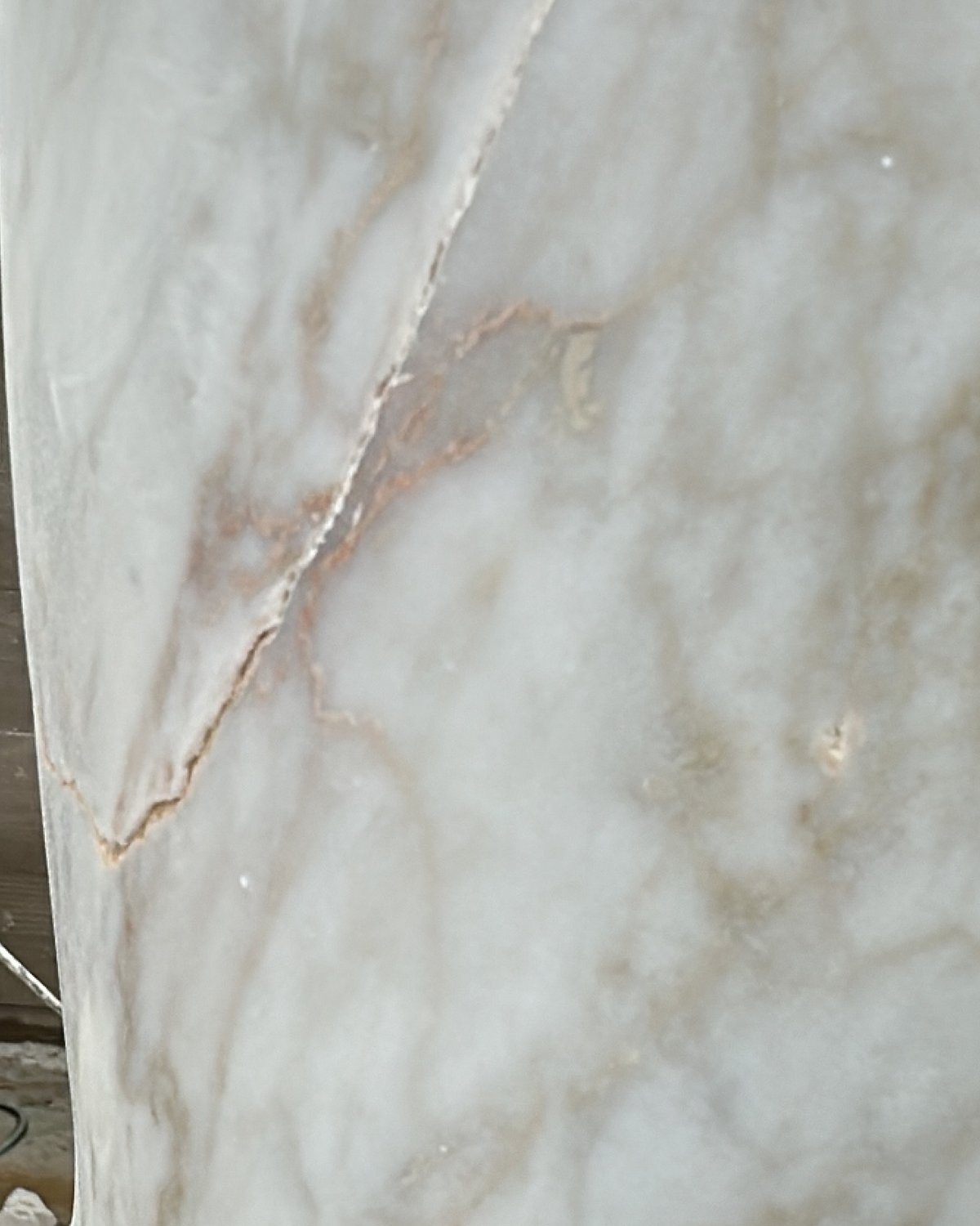 Close view of the white marble with a fine rust-coloured fissure running through it