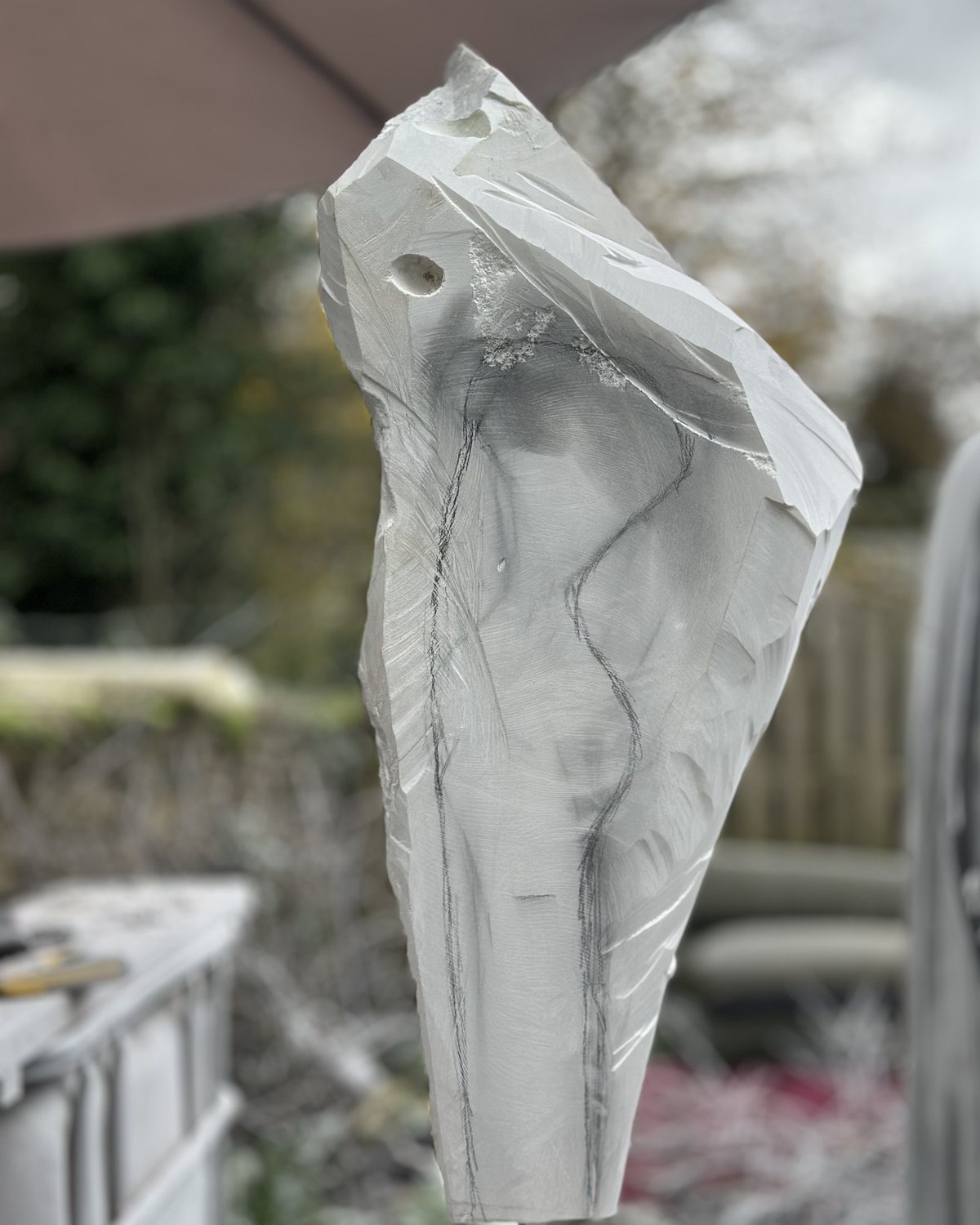 A rough block of white marble with a figure drawn on it in pencil