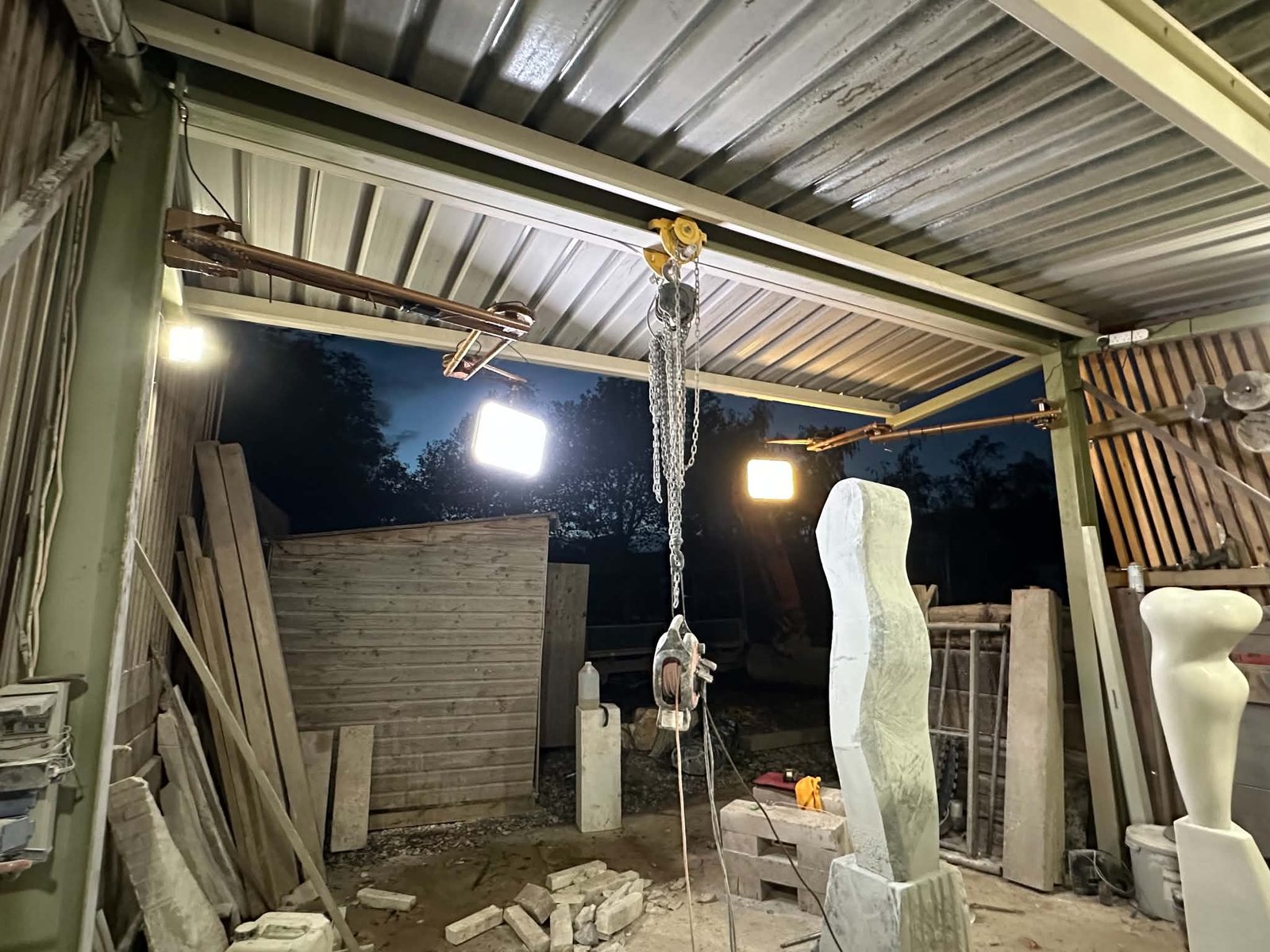 Marble figures in progress under the workshop floodlights at night