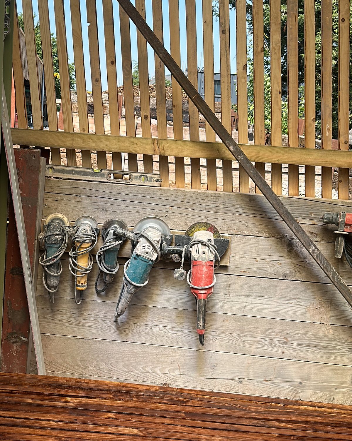 A row of angle grinders hanging on the timber wall of the workshop