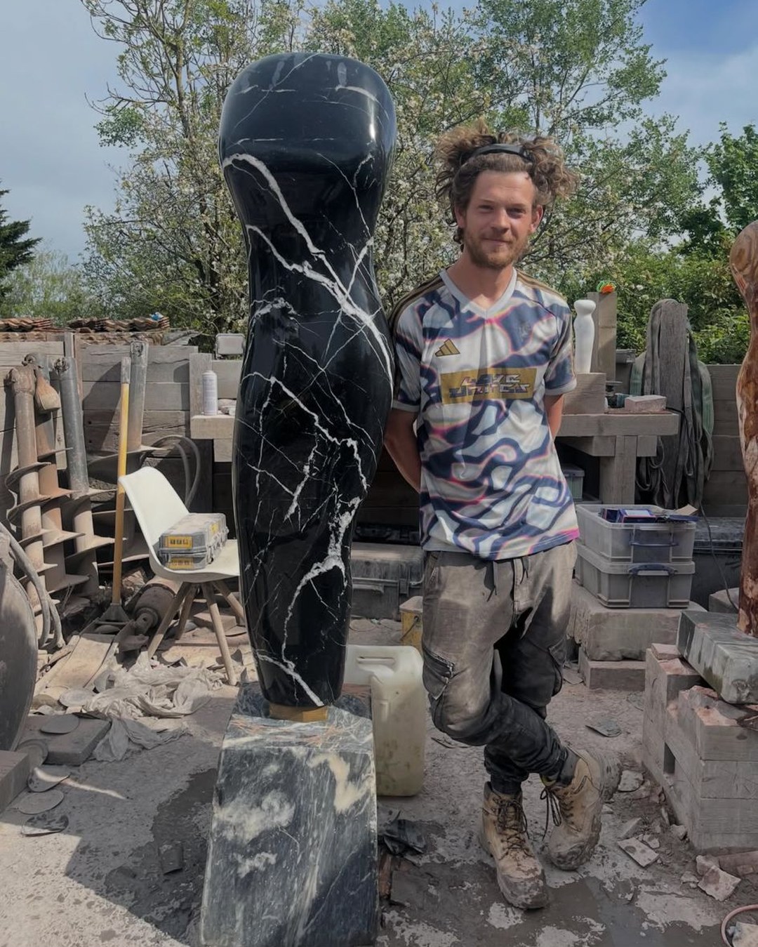Zak Stevens standing beside a tall figure in black marble with white veins